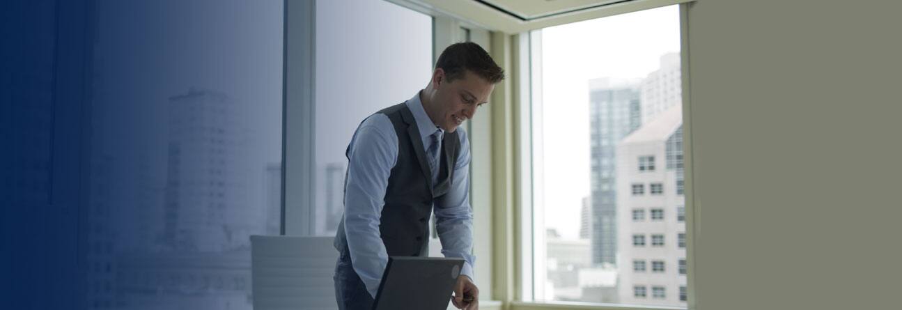 Man standing over desk in his office.