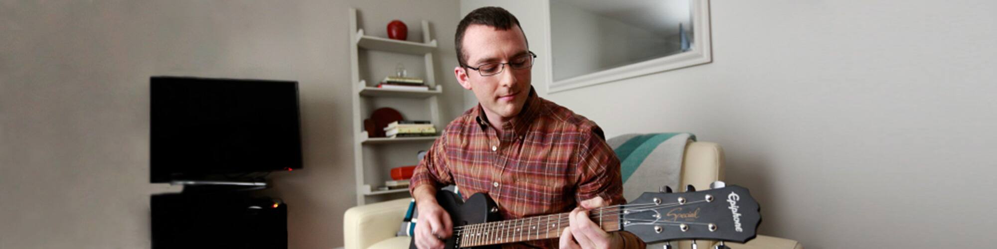 An SNHU graduate playing his guitar