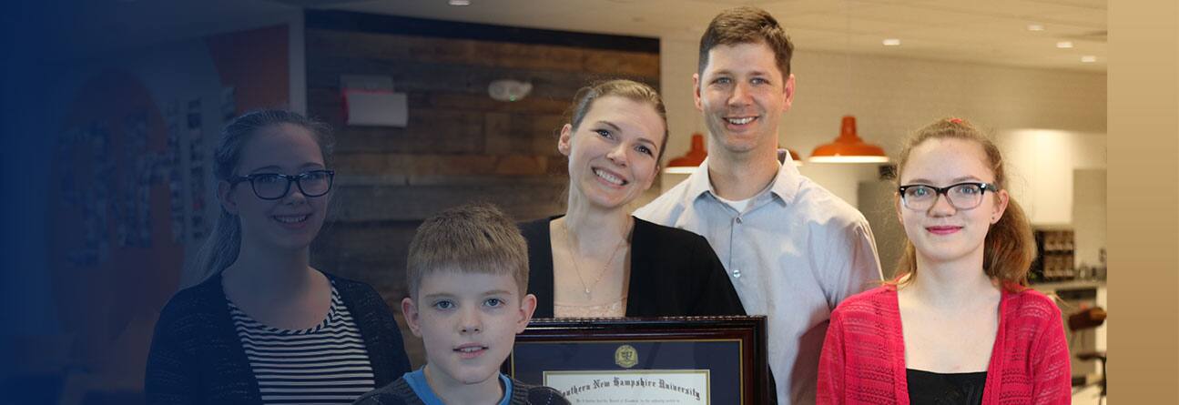 Military spouse with family holding an SNHU diploma