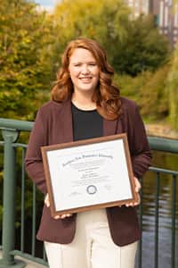 Ali Lamoureux holding diploma by river
