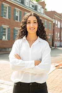 Fatma Salem Pease on sidewalk with arms cross smiling